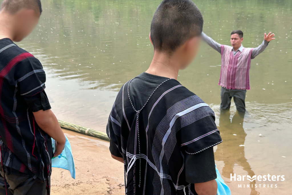 Pastor prays for two young men being baptised. Harvesters Ministries